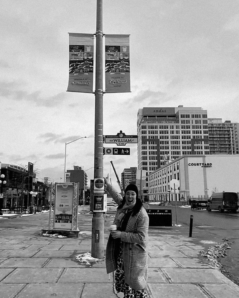 Victoria Williston pointing up at new ByWard Market street banners on William Street